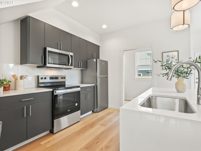 kitchen with stainless steel appliances, light countertops, a sink, modern cabinets, and dark cabinetry