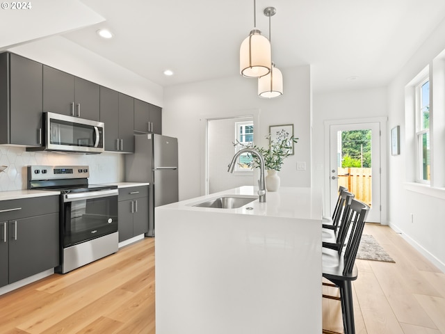 kitchen featuring decorative light fixtures, appliances with stainless steel finishes, decorative backsplash, and light hardwood / wood-style floors