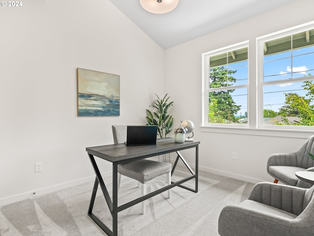 office area featuring light carpet, lofted ceiling, and baseboards