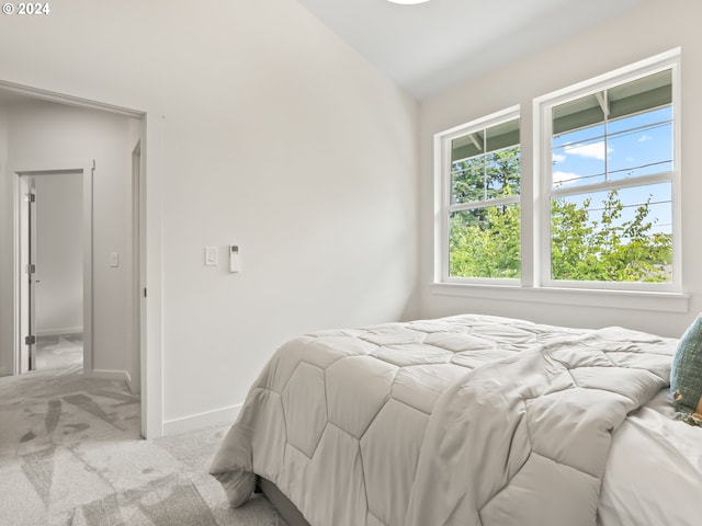 bedroom with light carpet, baseboards, and lofted ceiling