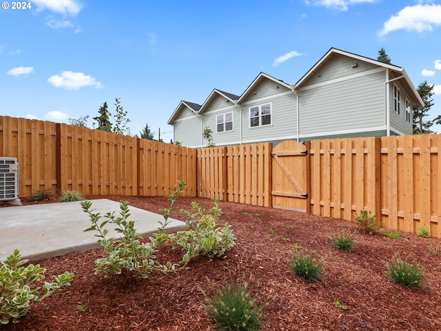 view of yard with central AC unit, a gate, fence, and a patio