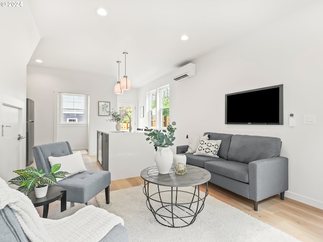 living area featuring a wall unit AC, light wood finished floors, baseboards, and recessed lighting