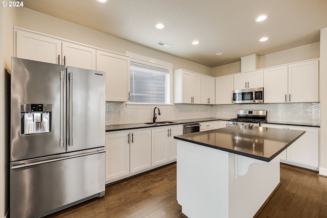 kitchen with a center island, stainless steel appliances, dark wood-type flooring, sink, and white cabinetry