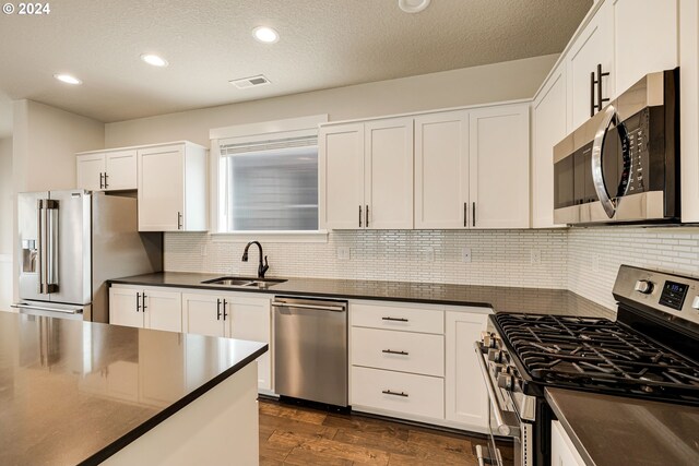 kitchen featuring dark hardwood / wood-style floors, white cabinets, appliances with stainless steel finishes, and sink