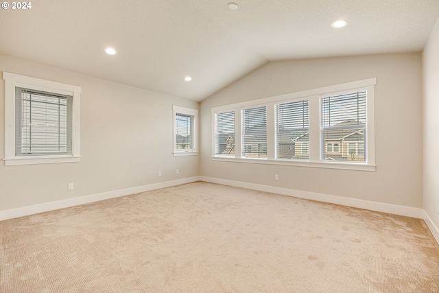 carpeted spare room with vaulted ceiling