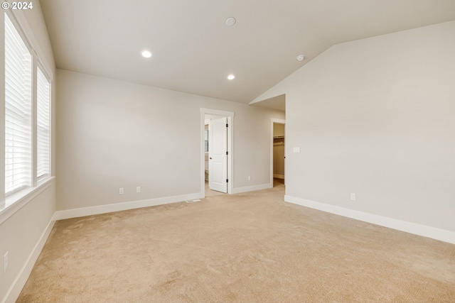 spare room with light carpet and lofted ceiling