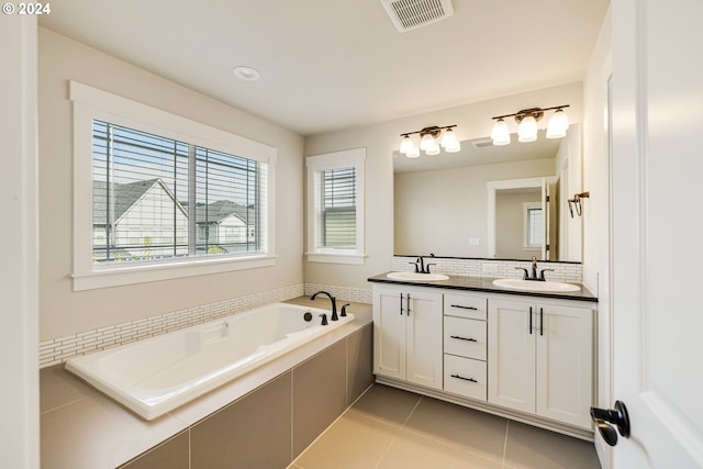 bathroom with tiled tub, vanity, and tile patterned floors