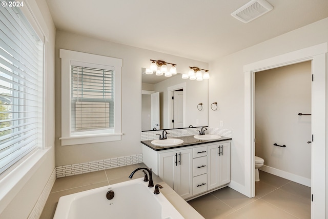 bathroom featuring vanity, a tub to relax in, tile patterned flooring, and toilet