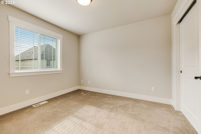 unfurnished bedroom with a closet and light colored carpet