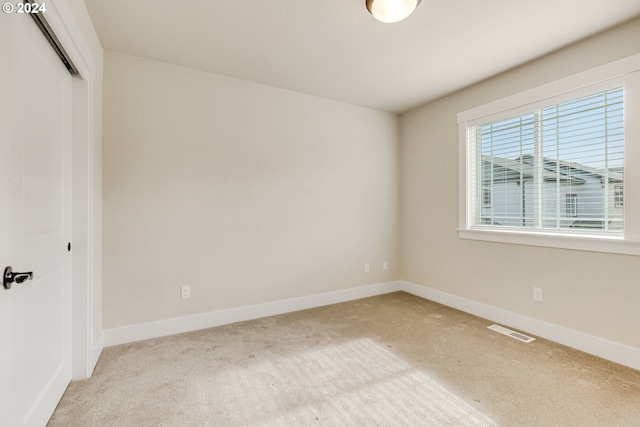 unfurnished bedroom featuring light carpet and a closet