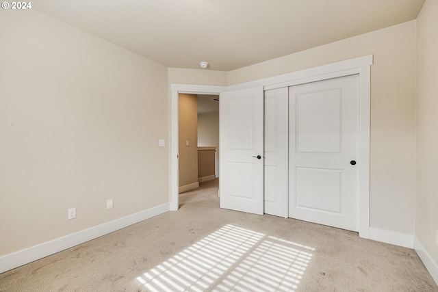 unfurnished bedroom featuring a closet and light colored carpet