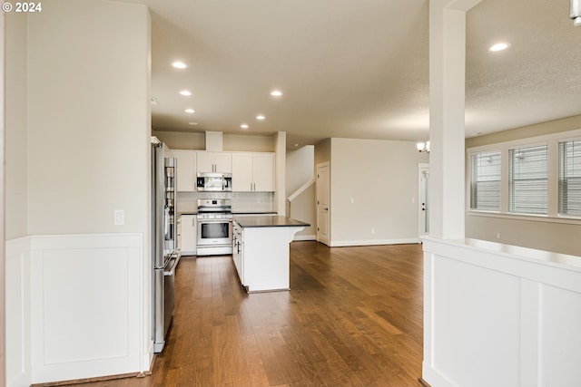 kitchen featuring a kitchen island, a breakfast bar area, dark hardwood / wood-style floors, white cabinets, and appliances with stainless steel finishes