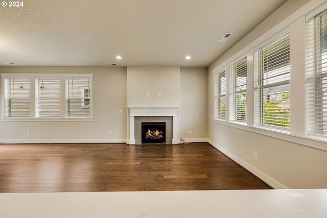 unfurnished living room with a textured ceiling, a fireplace, and dark hardwood / wood-style flooring