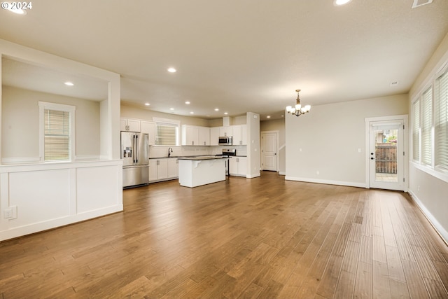 unfurnished living room with wood-type flooring, a notable chandelier, and sink