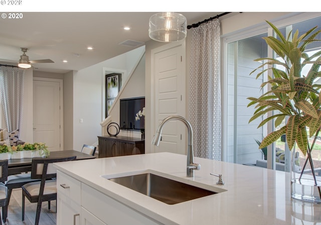 kitchen with white cabinets, ceiling fan, sink, and pendant lighting