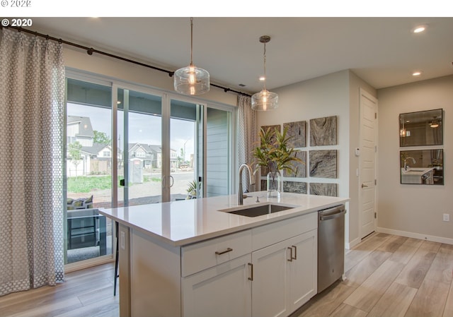 kitchen with sink, an island with sink, stainless steel dishwasher, white cabinets, and light hardwood / wood-style flooring