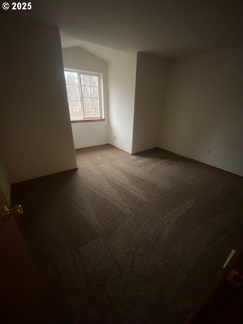 carpeted spare room with vaulted ceiling