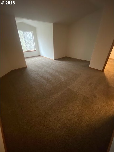 carpeted spare room with lofted ceiling