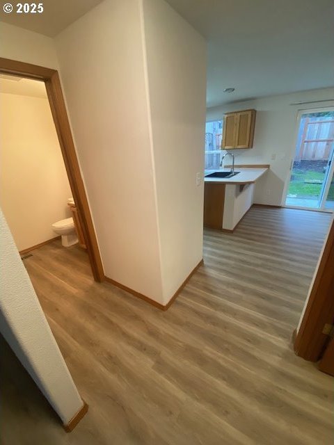 corridor with light hardwood / wood-style floors and sink