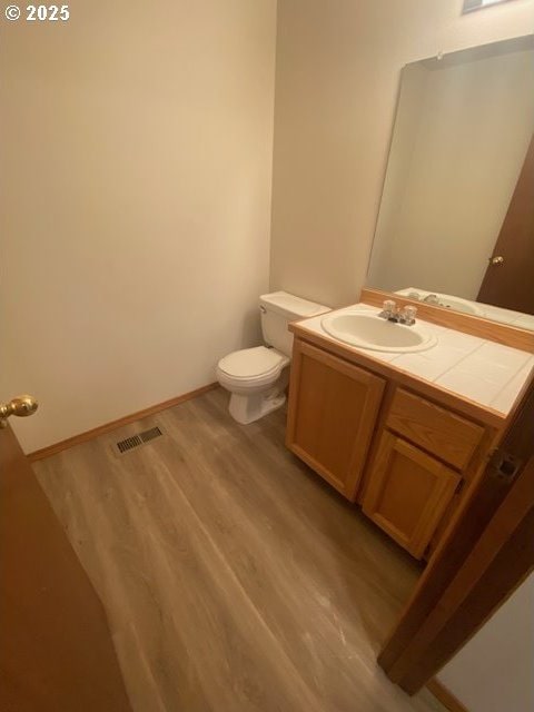 bathroom with vanity, toilet, and wood-type flooring