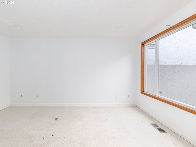 empty room with baseboards, visible vents, and light floors