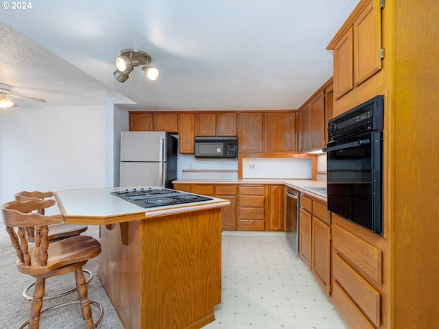 3242 NE 29th St, Gresham, OR 97030 - kitchen with black appliances, light floors, light countertops, a center island, and a kitchen breakfast bar
