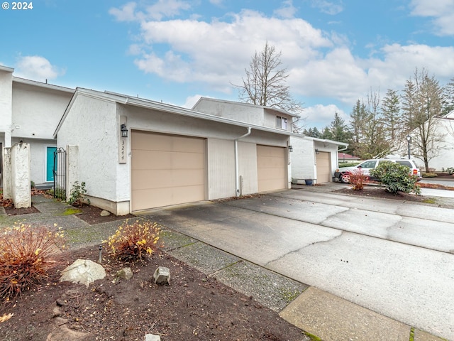 view of side of property with driveway, an attached garage, and stucco siding