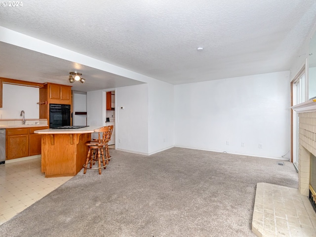 3242 NE 29th St, Gresham, OR 97030 - kitchen with black oven, a brick fireplace, open floor plan, a textured ceiling, and a kitchen breakfast bar