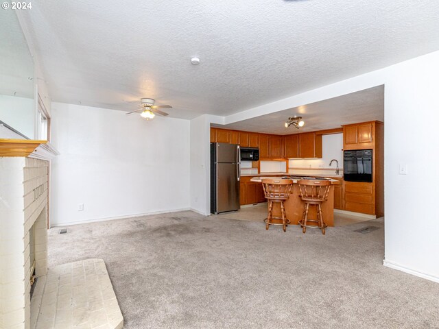 3242 NE 29th St, Gresham, OR 97030 - kitchen with black appliances, open floor plan, light carpet, a ceiling fan, and a textured ceiling