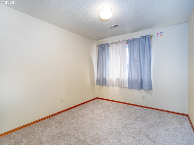 carpeted spare room featuring baseboards, visible vents, and a textured ceiling