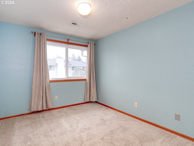 unfurnished room with a textured ceiling, a textured wall, carpet flooring, visible vents, and baseboards