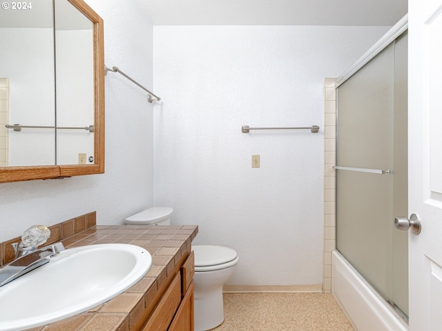 bathroom featuring enclosed tub / shower combo, vanity, and toilet