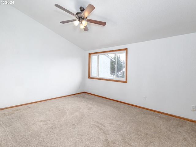 spare room with carpet floors, vaulted ceiling, baseboards, and a ceiling fan