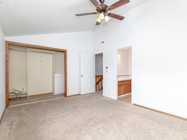 unfurnished bedroom featuring lofted ceiling, a textured ceiling, and light colored carpet