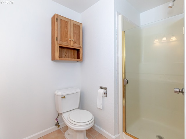 bathroom with baseboards, a shower stall, toilet, and tile patterned floors