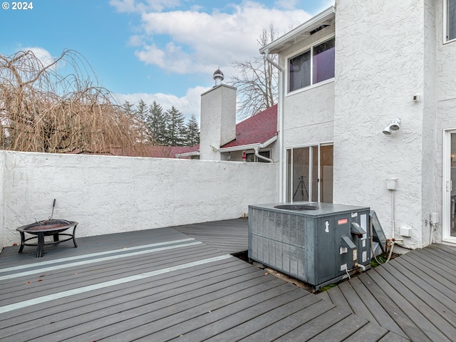 deck featuring an outdoor fire pit, fence, and central AC unit