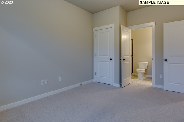 unfurnished bedroom featuring light carpet and ensuite bathroom