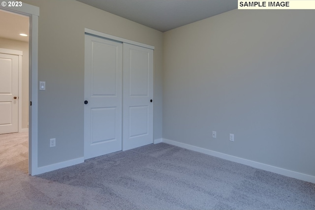 unfurnished bedroom with a closet and light colored carpet