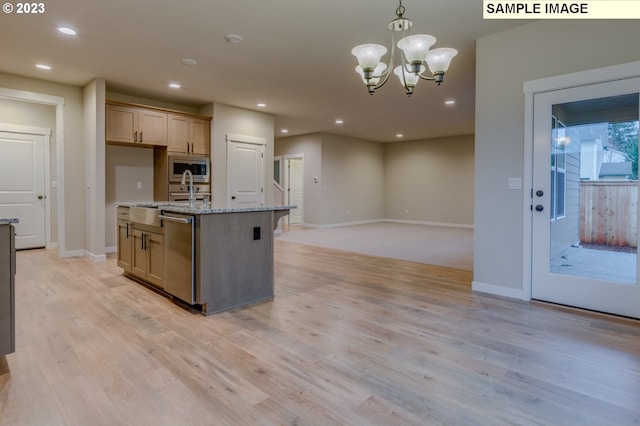 kitchen featuring light brown cabinets, a center island with sink, light stone counters, pendant lighting, and stainless steel appliances