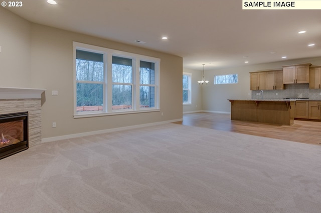 unfurnished living room featuring a chandelier and light colored carpet