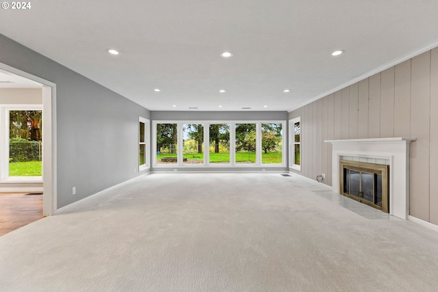 unfurnished living room featuring crown molding, light colored carpet, and plenty of natural light