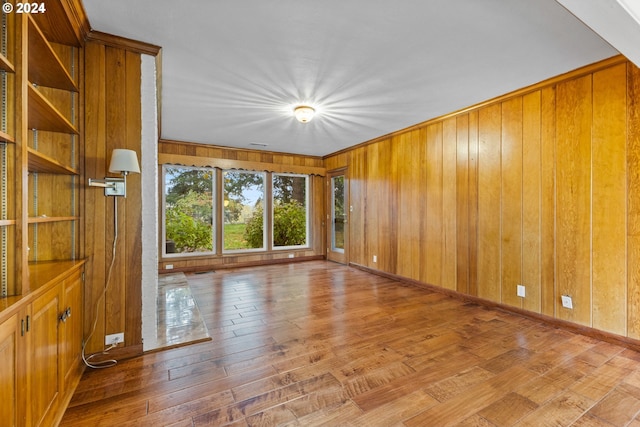 spare room with light hardwood / wood-style floors and wooden walls