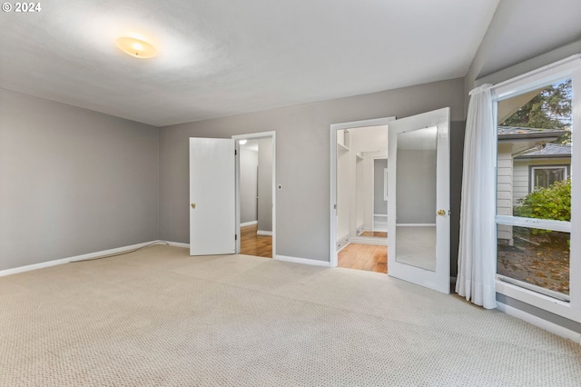 unfurnished bedroom featuring connected bathroom and light carpet