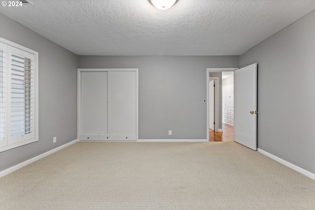 unfurnished bedroom featuring a textured ceiling and light colored carpet