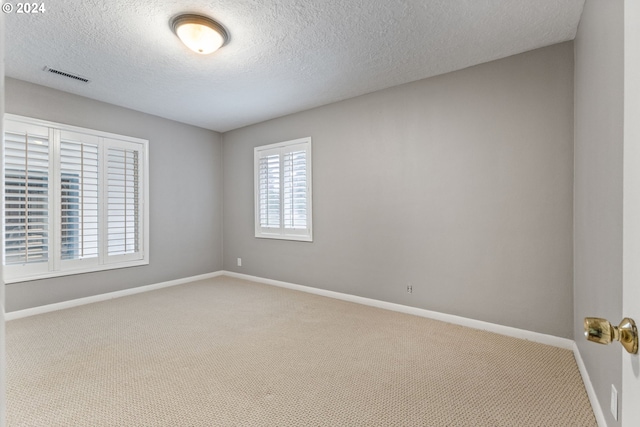 carpeted spare room with a textured ceiling