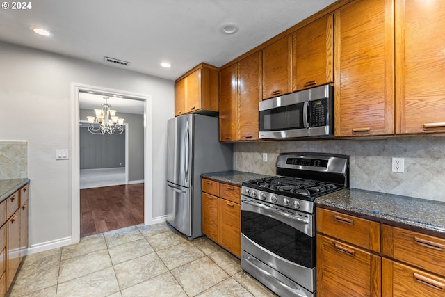 kitchen with an inviting chandelier, tasteful backsplash, stainless steel appliances, and light tile patterned floors