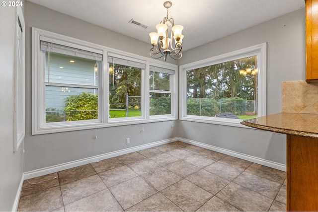 unfurnished dining area with light tile patterned floors, an inviting chandelier, and plenty of natural light