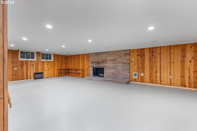 unfurnished living room featuring concrete floors, wood walls, and a fireplace