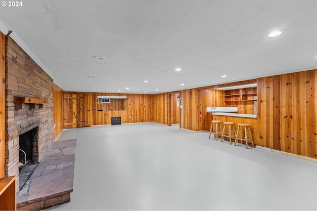 interior space with wood walls, a fireplace, a textured ceiling, bar, and ornamental molding