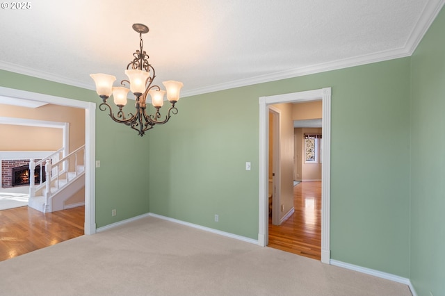 unfurnished room featuring a fireplace, a chandelier, carpet flooring, and ornamental molding